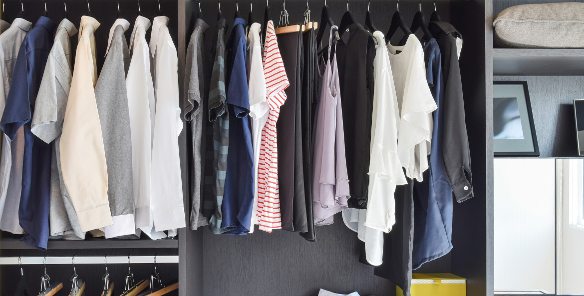 minimalist black, white, gray, and pink wardrobe hangs in an organized modern closet, image
