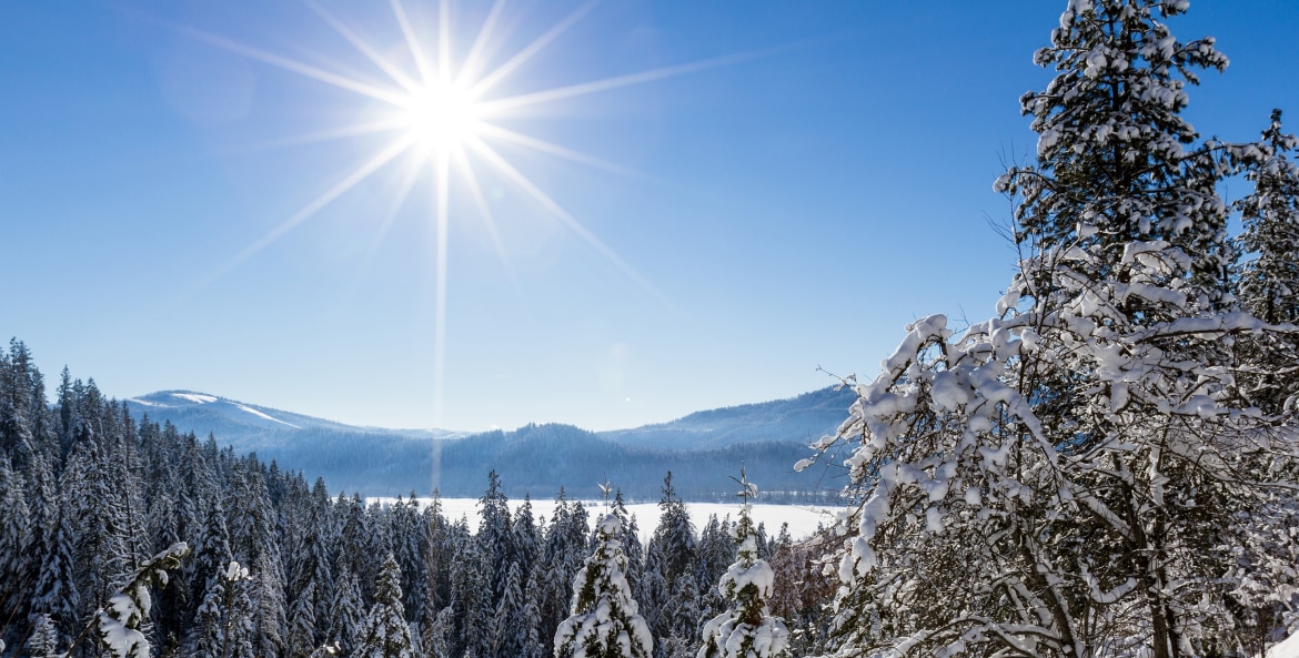 Beautiful view of the snow-covered forest opening to reveal a piece of Lake Coeur d' Alene on a sunny winter afternoon, picture