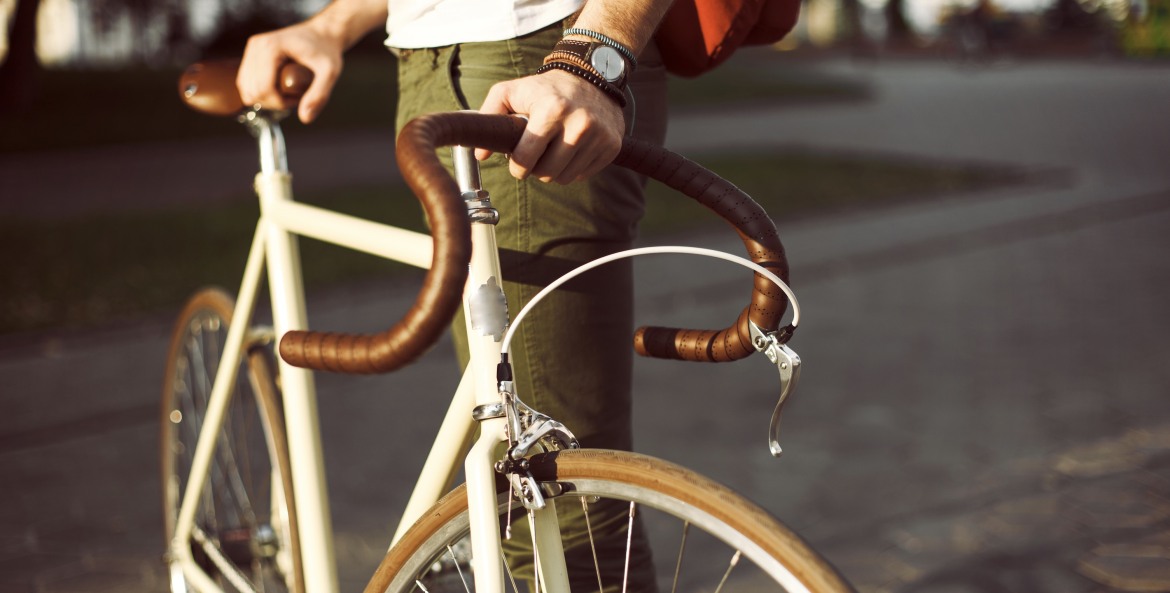 picture of a young man holding a white bicycle in the sun