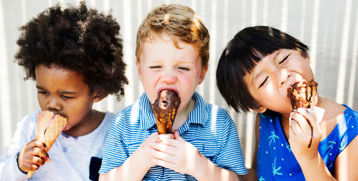 Three boys eat ice cream cones in the shade on a summer day, image
