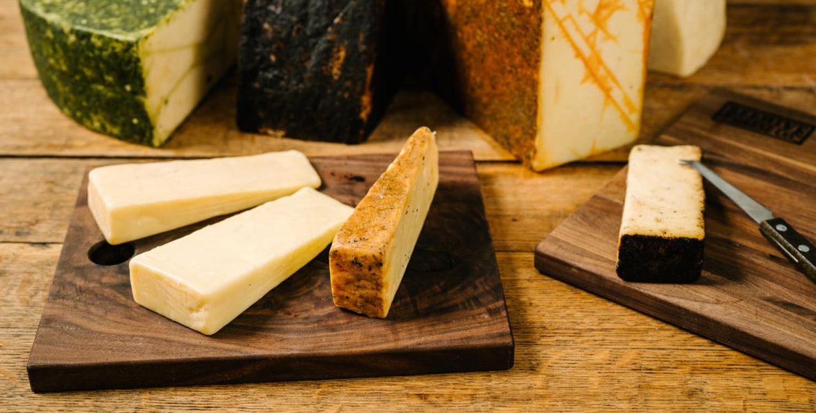 Cutting board displaying multiple cheese varieties, picture