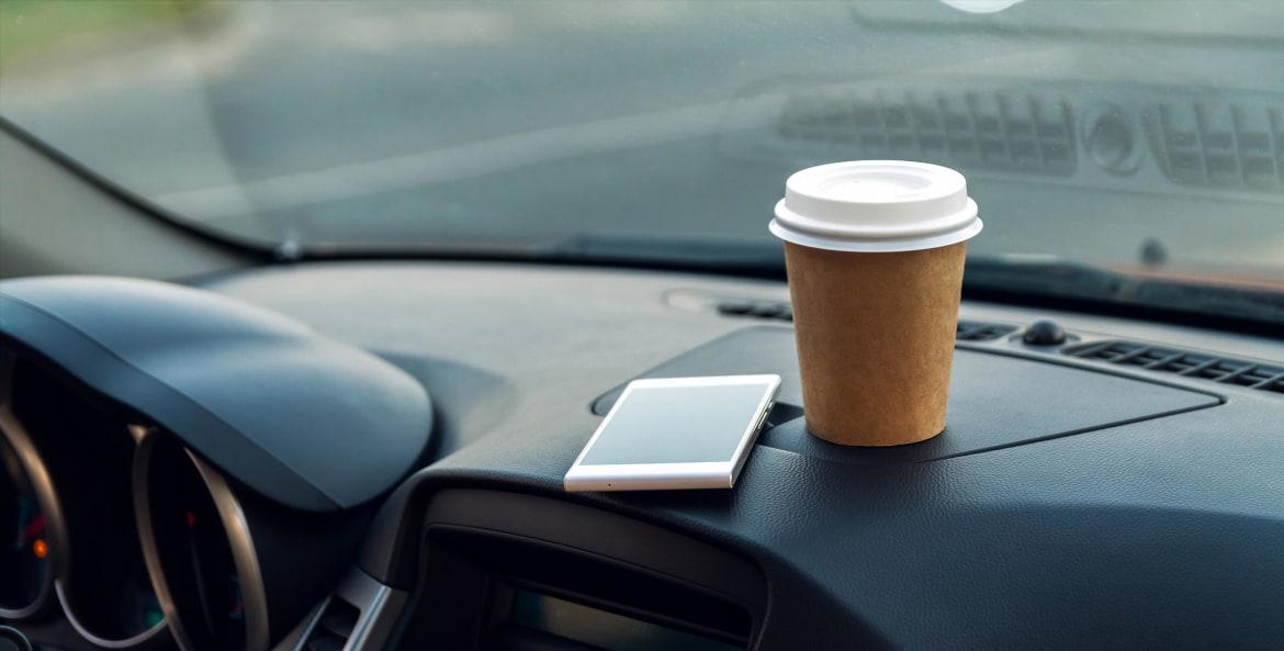 car dashboard with a cell phone and cup of coffee, image