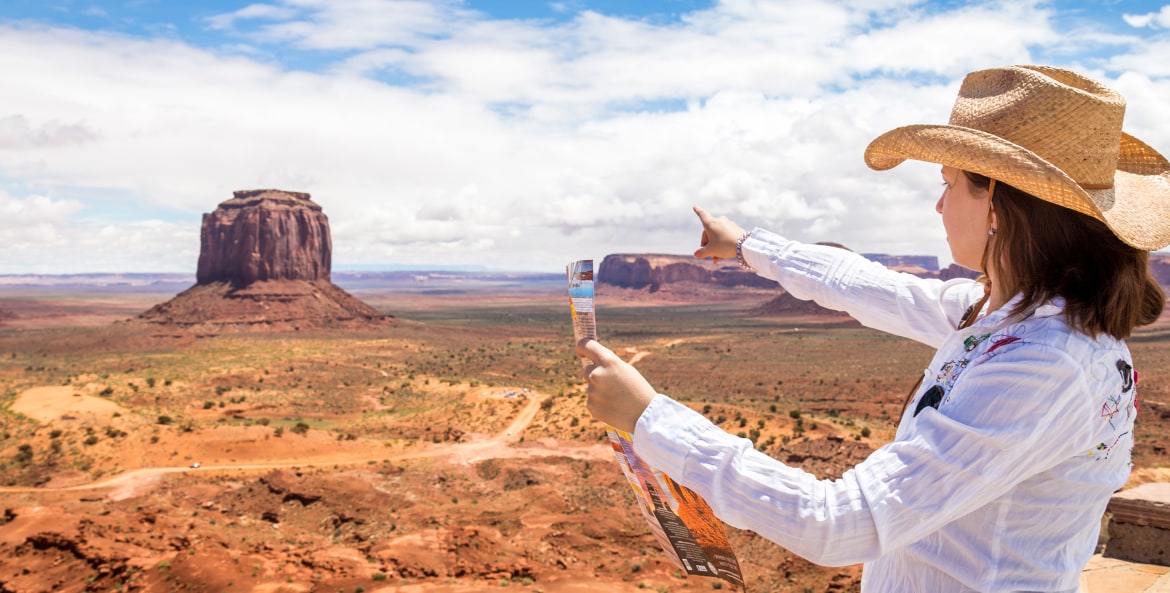 Woman in straw hat points to Monument Valley in Utah, image