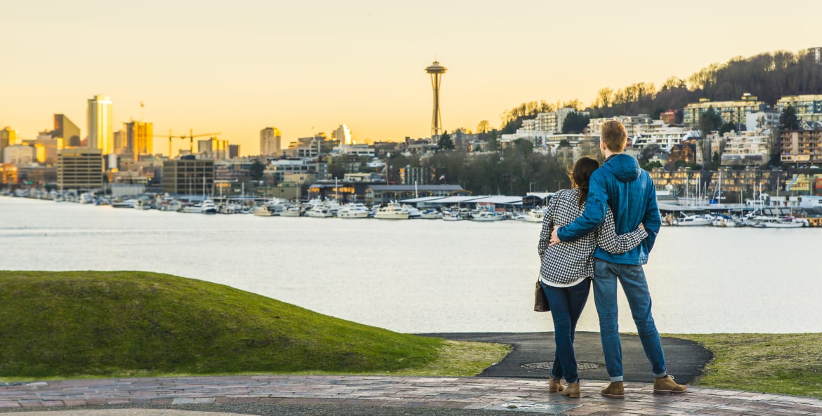 a couple looks out at the Seattle skyline, picture