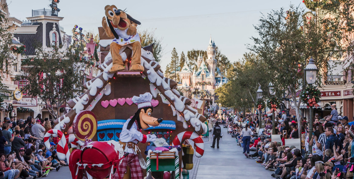 a picture of Goofy on a gingerbread house float during the daily Christmas parade at Disneyland