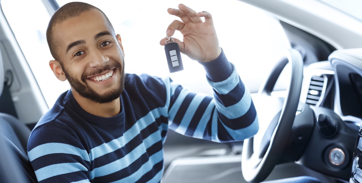 picture of a young man in a brand-new car holding keys