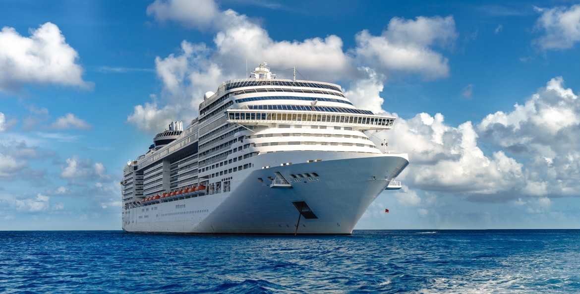 picture of a cruise ship on the open ocean with a blue sky and clouds in the background