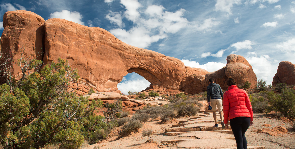 A couple hike to North Window in Arches National Park, Moab, Utah