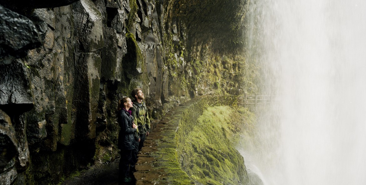 woman and man take in the view from behind a waterfall at Oregon's Silver Falls State Park, picture