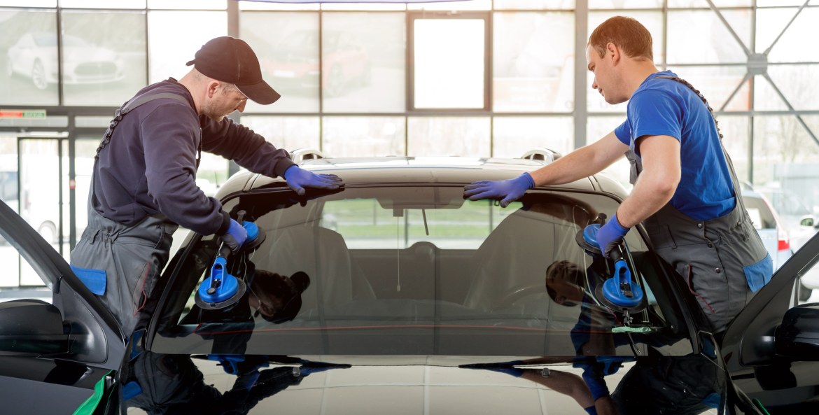 Windshield replacement specialists install new glass on a small car.