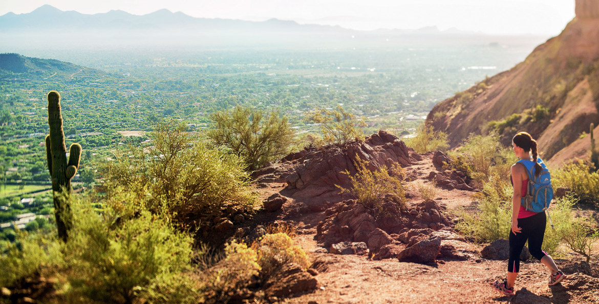 Woman hikes Echo Canyon Trail on Camelback Mountain in Phoenix, Arizona on a sunny day overlooking the city, picture