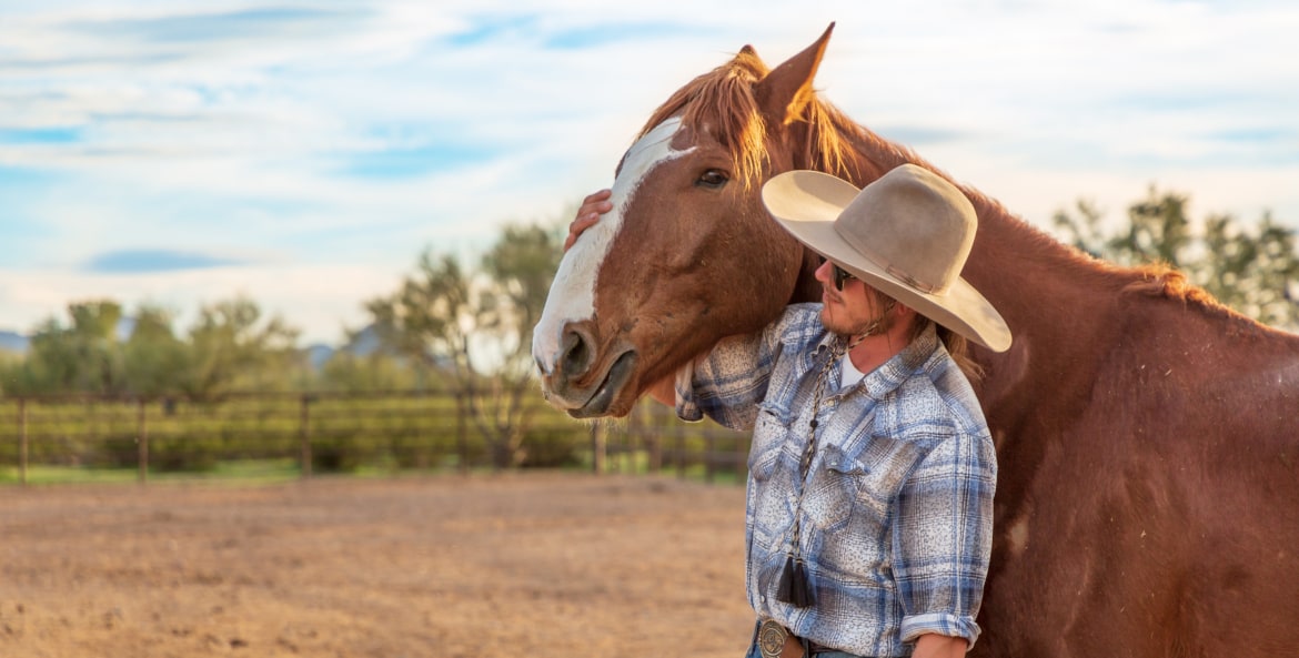 a ranch hand strokes a horse's nose at White Stallion Ranch outside Tucson, image