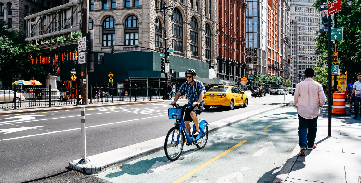 A man rides a shared bike on a protected bike lane in New York City