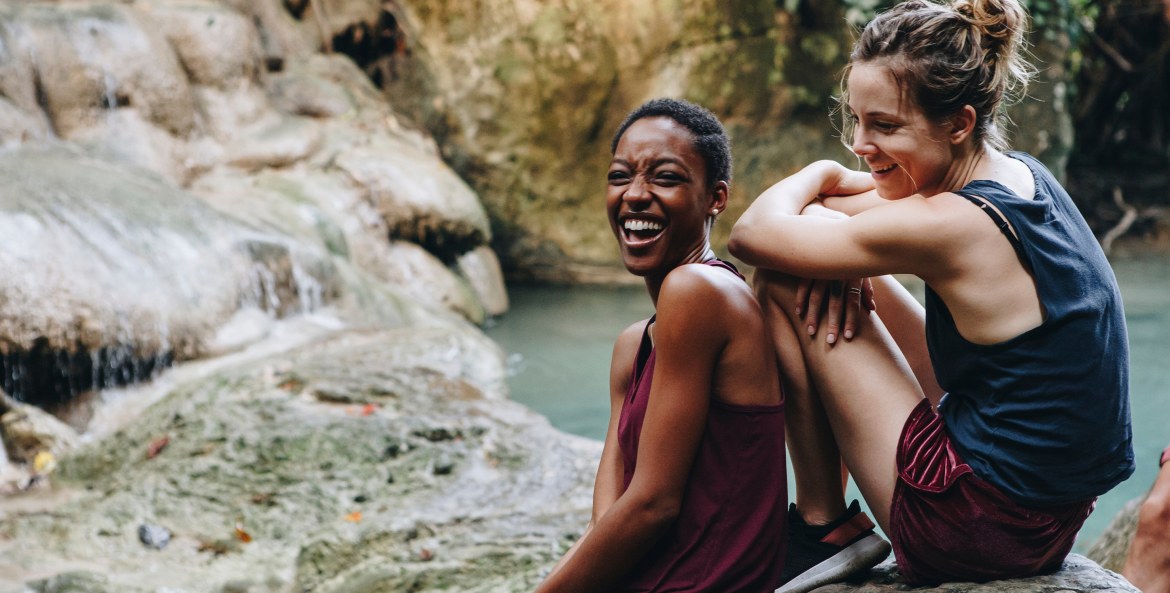 Two women laugh while resting on a hike, image