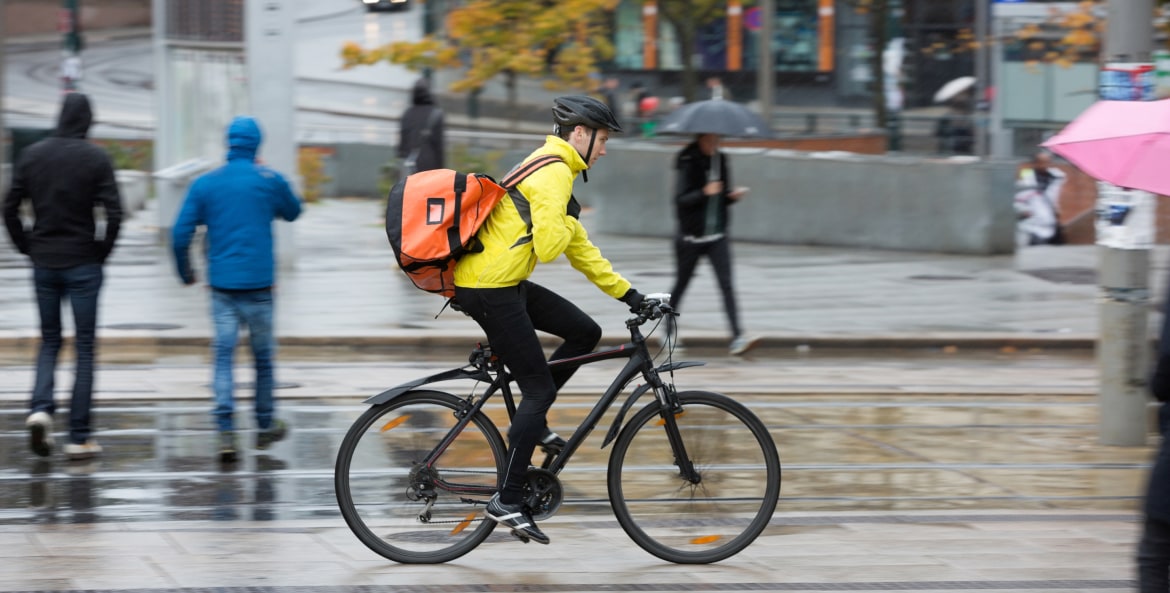 bicyclist in a helmet and bright clothes on a city street, image