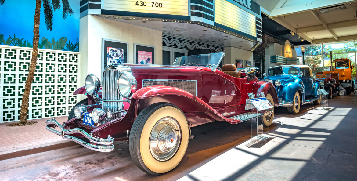 A vintage car in front of a marquee inside a museum, picture