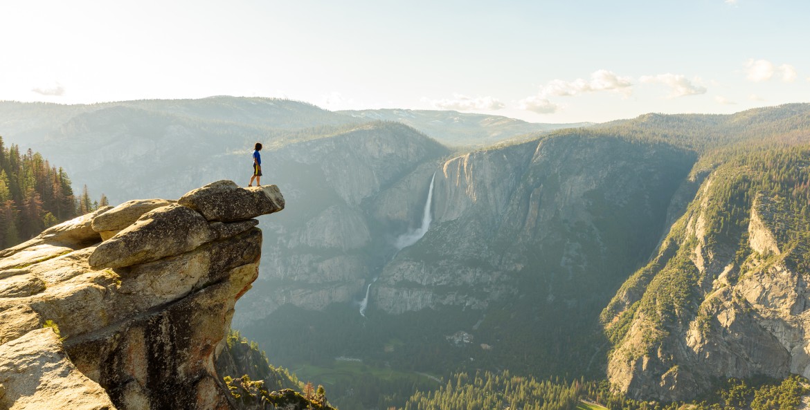 A hiker stands at Glacier Point overlooking the Yosemite Valley, image