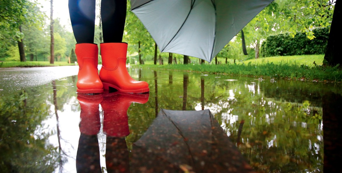 A person stands in a puddle in rubber boots.
