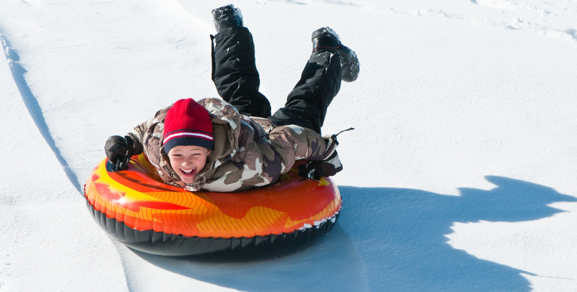 boy having fun on an inner tube in the snow, Sierra Nevada