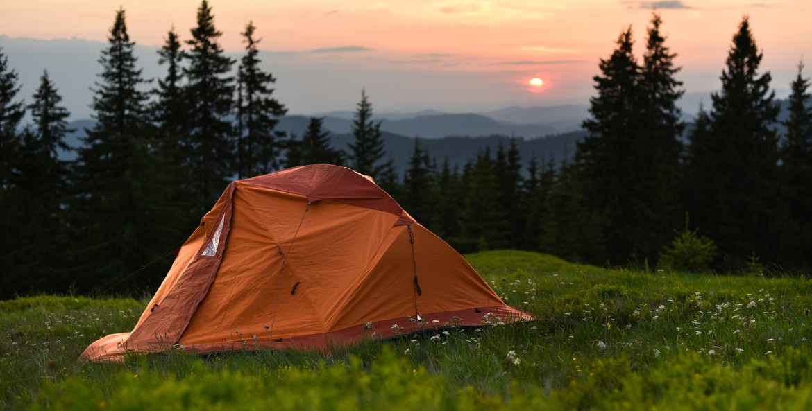 tent on a hill overlooking mountains at sunset, image