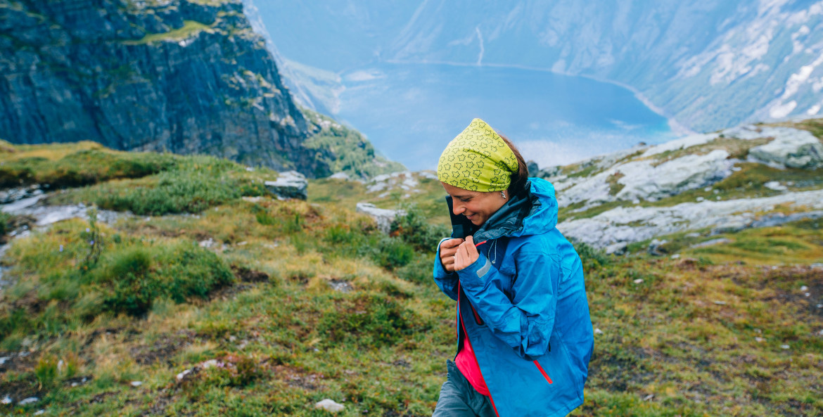 A hiker puts on a rain coat near a fjord in Norway.