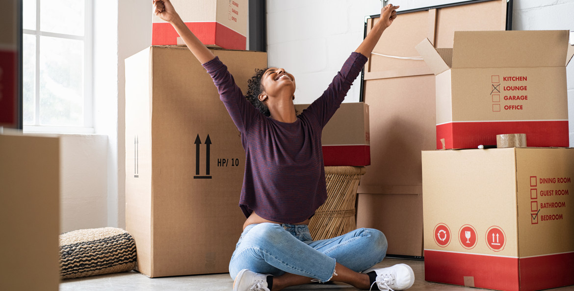 A woman sits in front of boxes in her new apartment.