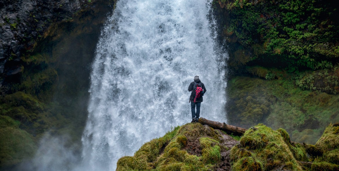 hiker takes in view of Sahalie Falls from moss-covered rock, near Sisters, Oregon
