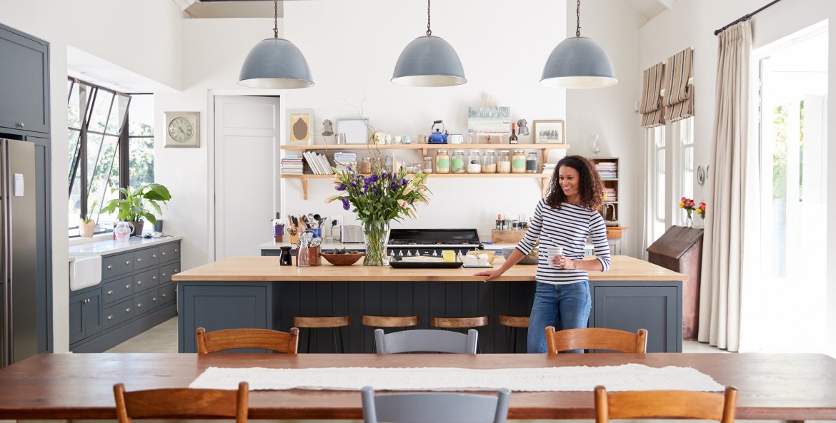 A woman stands in her bright modern kitchen.
