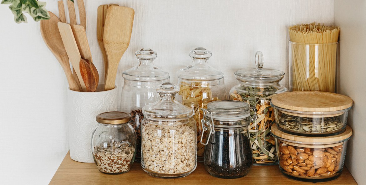 Glass jars with pantry staples on an open shelf.