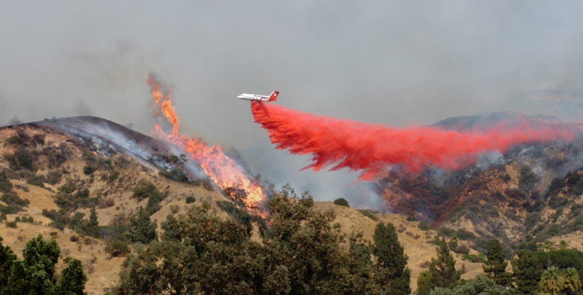 An airplane drops fire retardant on a wildifre in California.
