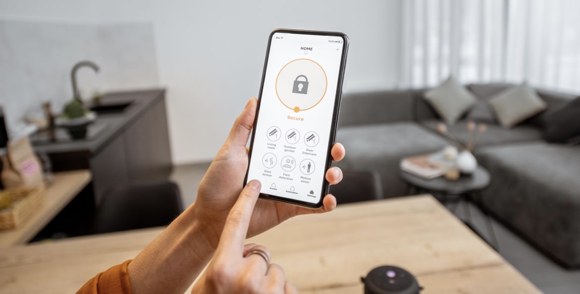 a hand holds a smartphone and uses a home security app