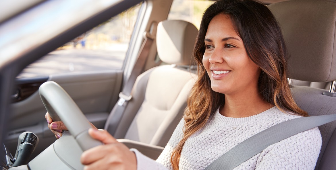 Happy woman driving a sedan.