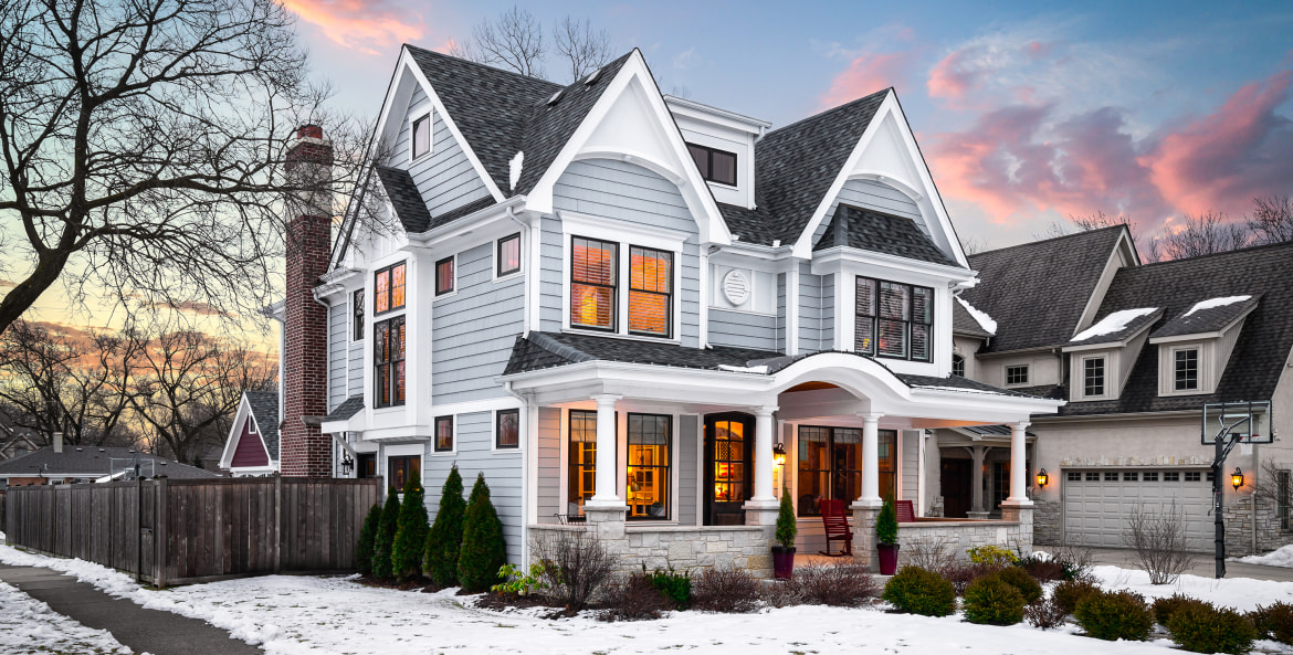A light dusting of snow surrounds a suburban home at sunset.