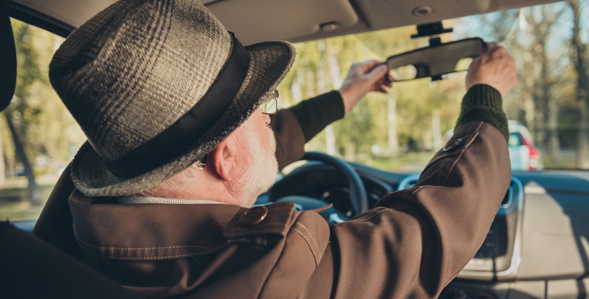 Elderly driver adjusting his mirror.