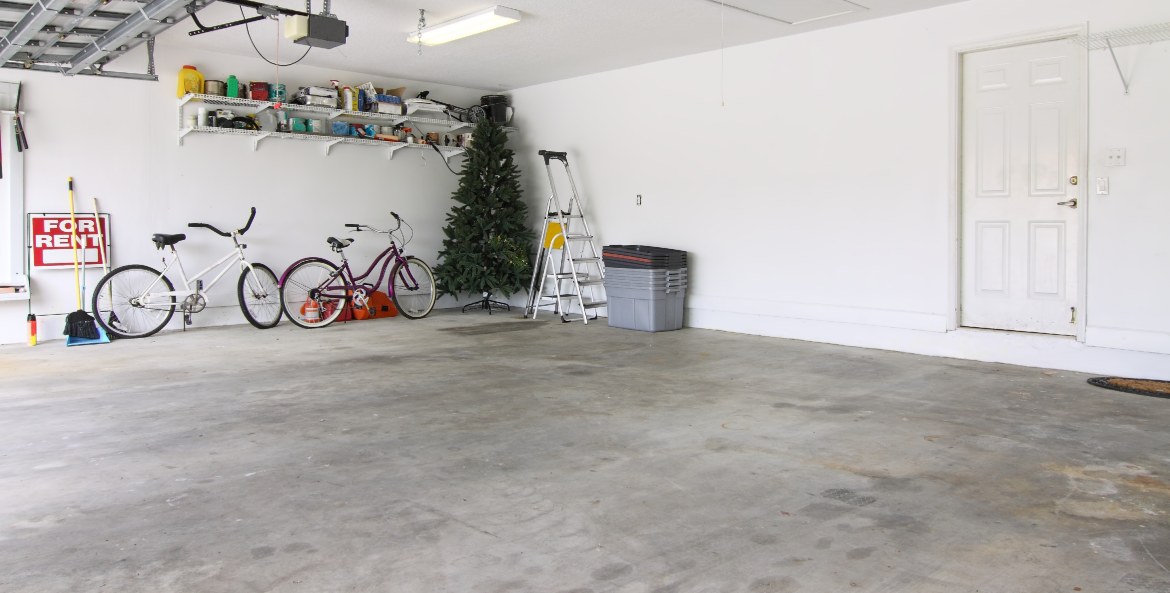 A nearly empty garage with a fake Christmas tree and bikes inside.