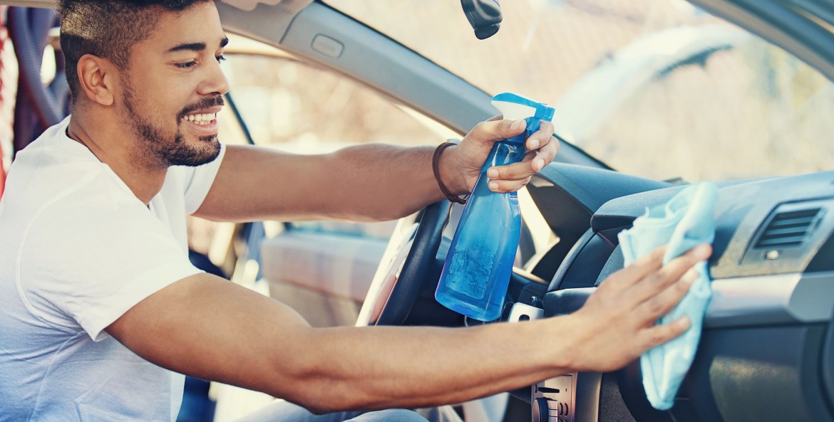AAA Member cleans his car's dashboard with a sanitizing spray and a microfiber cloth.