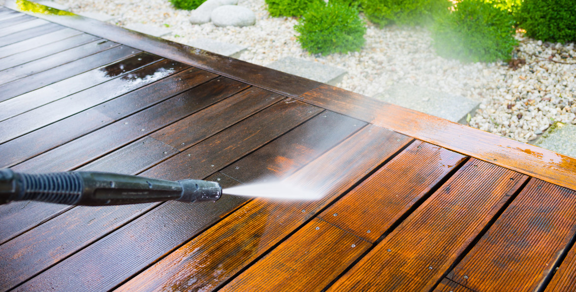 A homeowner pressure washes their deck.