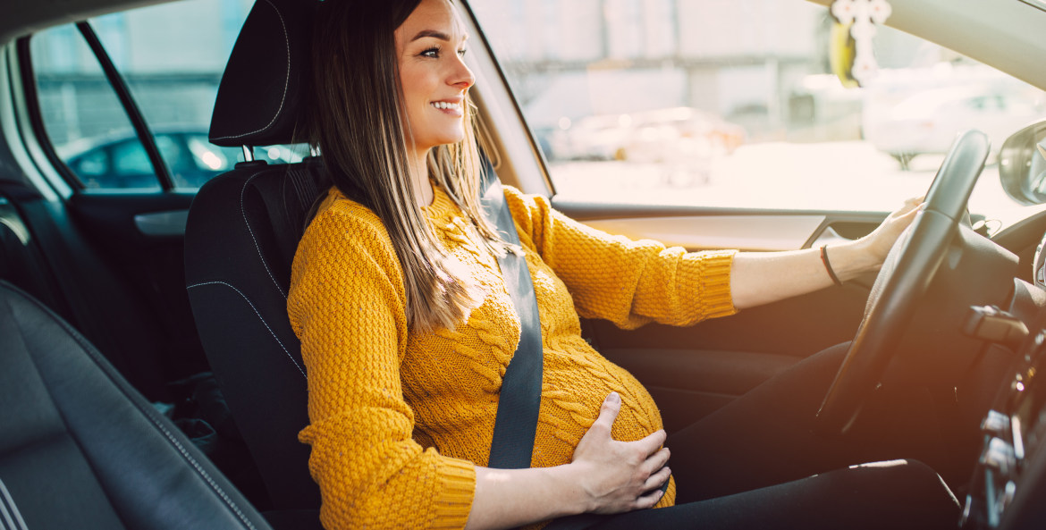 A pregnant woman drives her car.