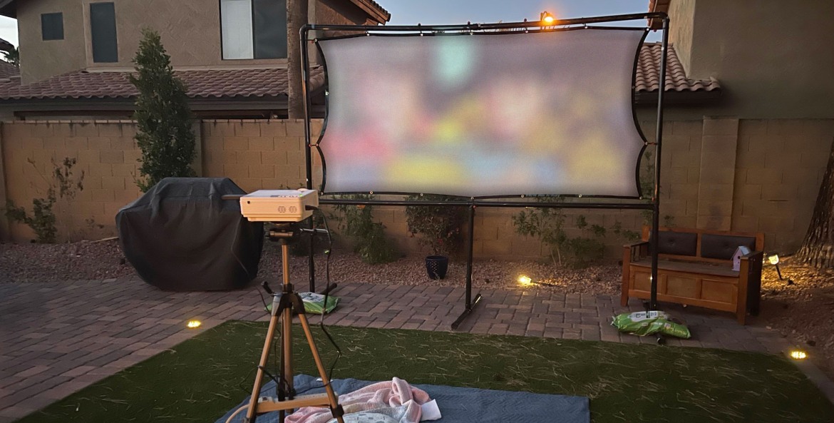 A projector plays a movie on a DIY projector screen.