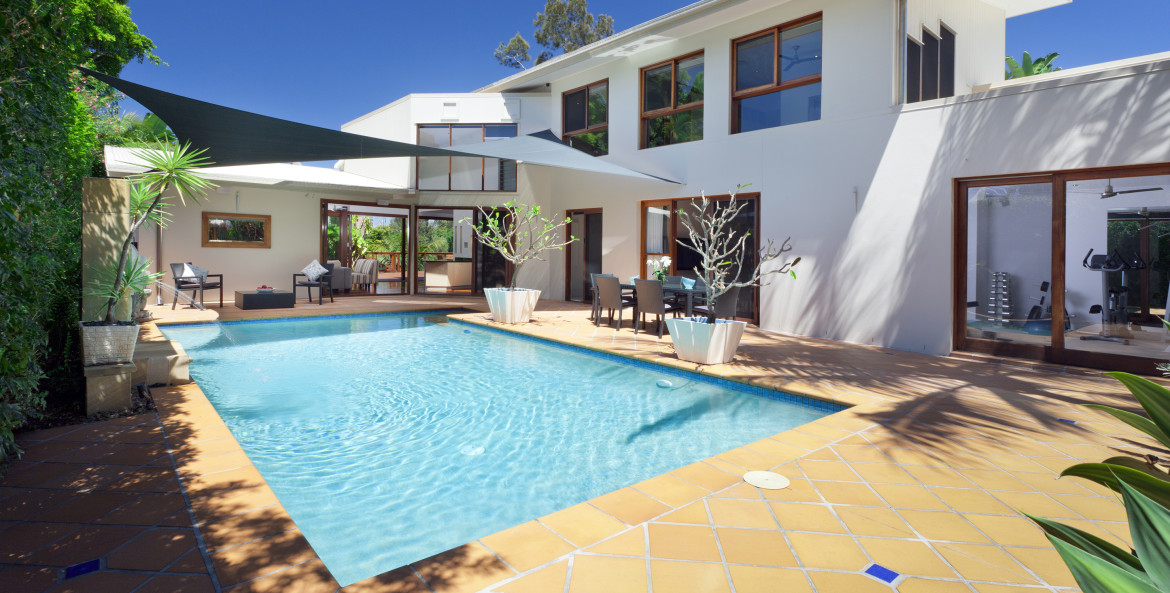 A beautiful pool in the backyard of a modern white home.