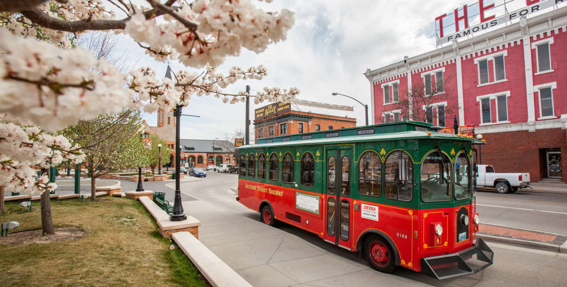 The Cheyenne Street Railway Trolley waits for new riders amid blooming trees in downtown Cheyenne, Wyoming.
