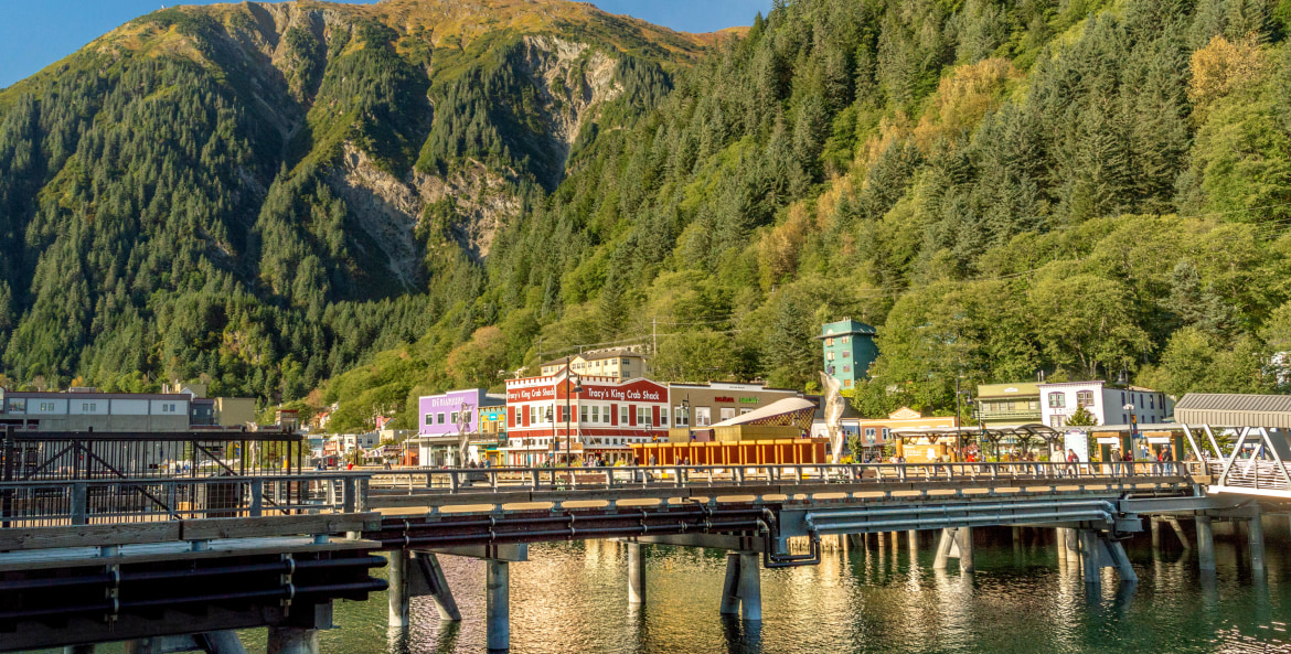Colorful buildings and the pier reflect off the water in Juneau, Alaska.