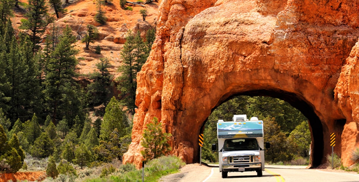 An RV drives thorugh a red rock tunnel just outside of Bryce Canyon National Park in Utah.