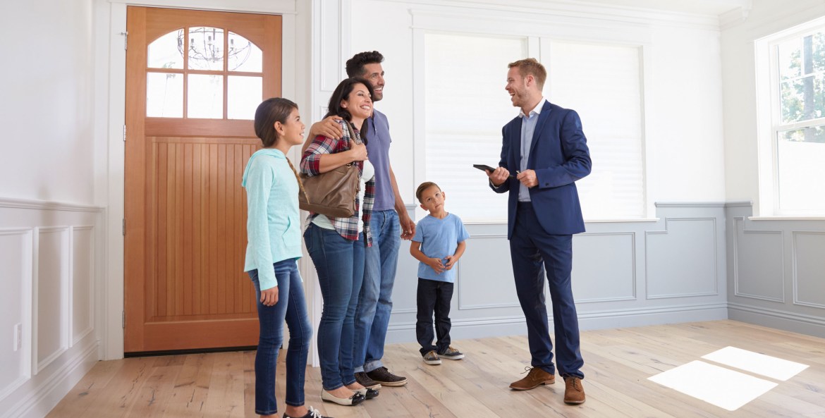 A family tours a house with a real estate agent.