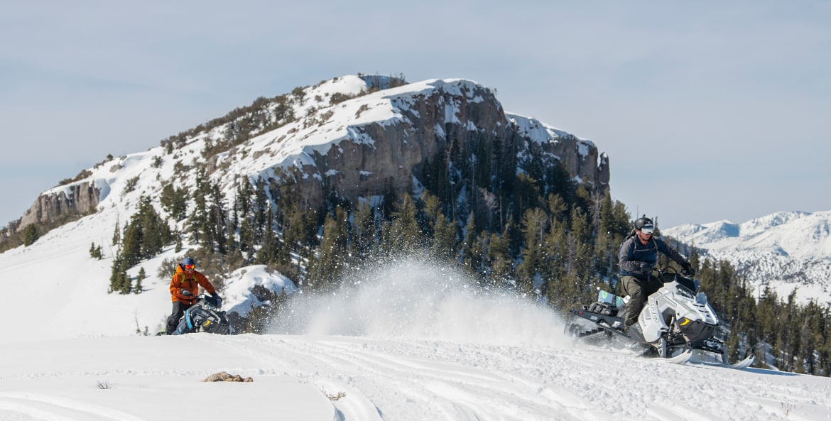 two people on snomobiles carve through fresh poweder in Ely, Nevada.