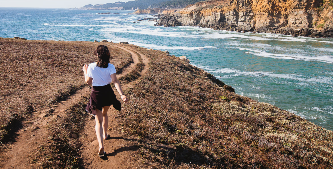 a woman walks on the bluff at California's Salt Point State Park.