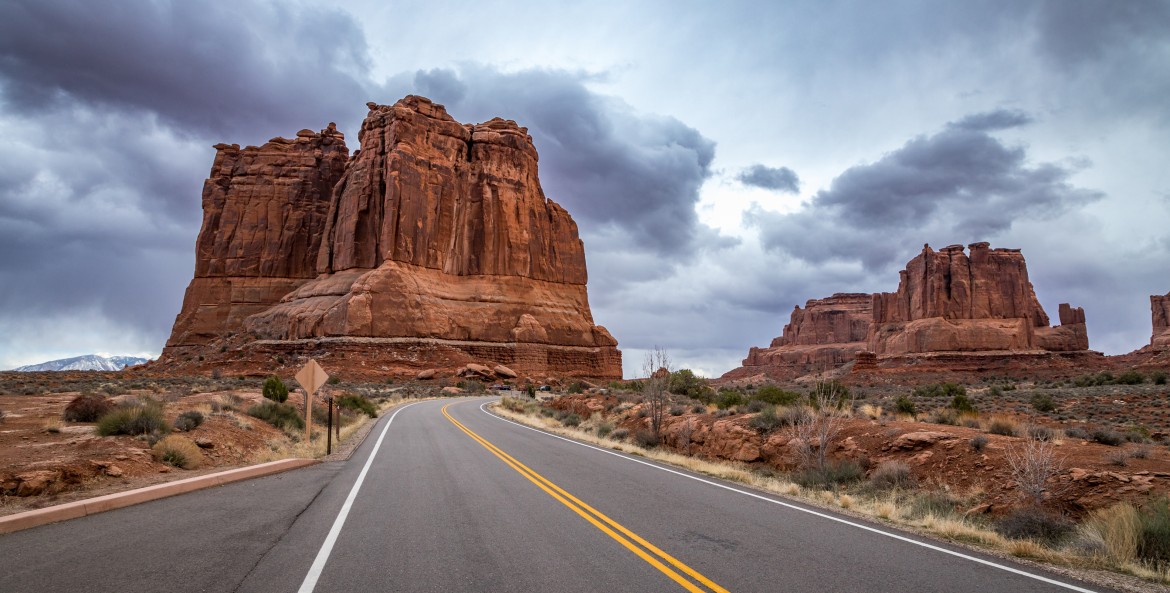 The Organ sandstone rock tower seen along Arches Scenic Drive with dramatic storm clouds looming overhead in Arches National Park, Moab, Utah.
