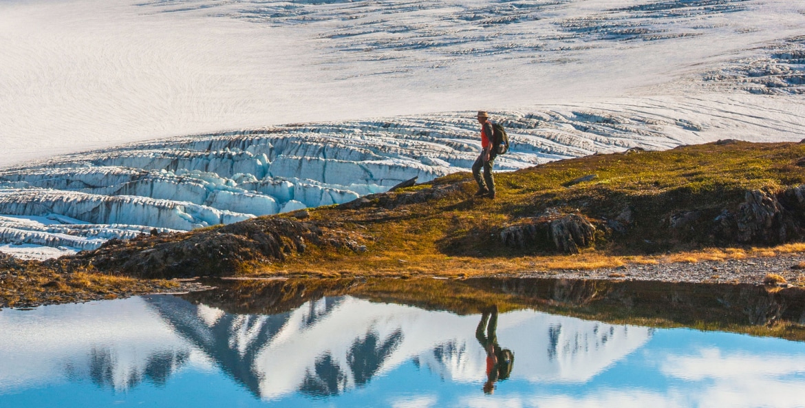 A man hikes past the Harding Icefield with the Nunatak peaks in the background in Kenai Fjords National Park.