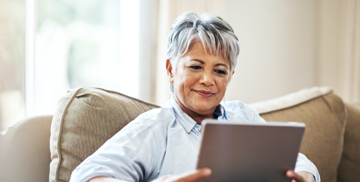 A woman sitting on the couch using a tablet