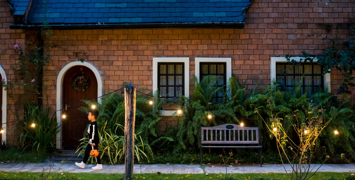 A child walks by string lights on Halloween.